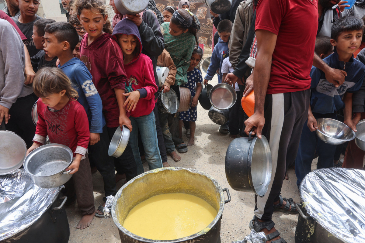Palestinos fazem fila para receber comida quente de uma cozinha beneficente instalada no campus da Universidade Islâmica na Cidade de Gaza