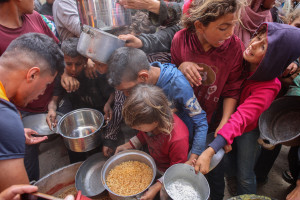 Palestinos se apressam para obter comida quente de uma cozinha de caridade instalada no campus da Universidade Isl&acirc;mica na Cidade de Gaza