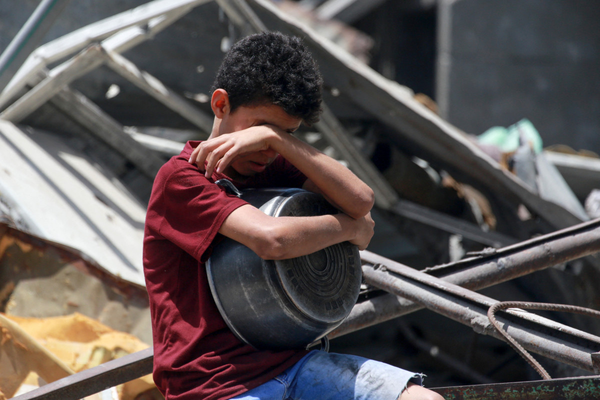 Menino gesticula enquanto palestinos deslocados coletam porções de comida cozida em uma distribuição de caridade em Jabalia, no norte da Faixa de Gaza(Bashar TALEB/AFP) Menino gesticula enquanto palestinos deslocados coletam porções de comida cozida em uma distribuição de caridade em Jabalia, no norte da Faixa de Gaza/Bashar TALEB/AFP