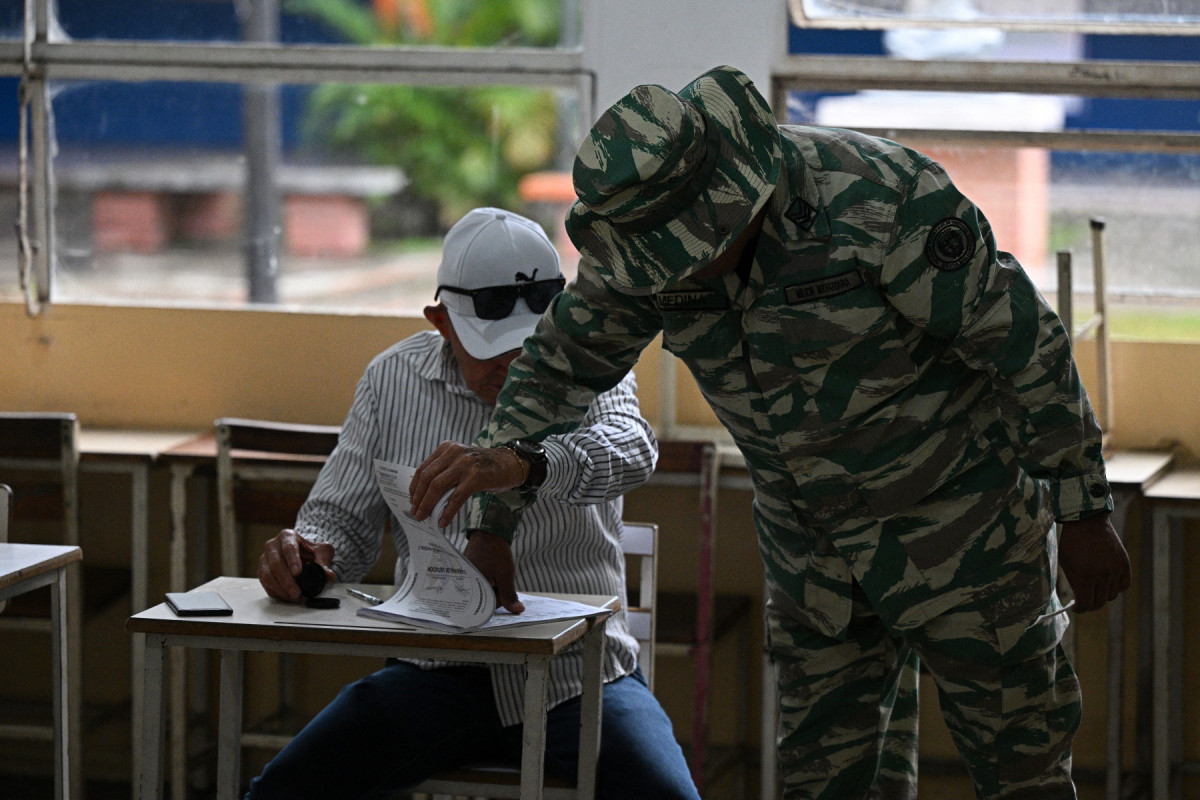 Um membro da Milícia Bolivariana verifica um livro de votação durante as eleições regionais em uma seção eleitoral em Caracas