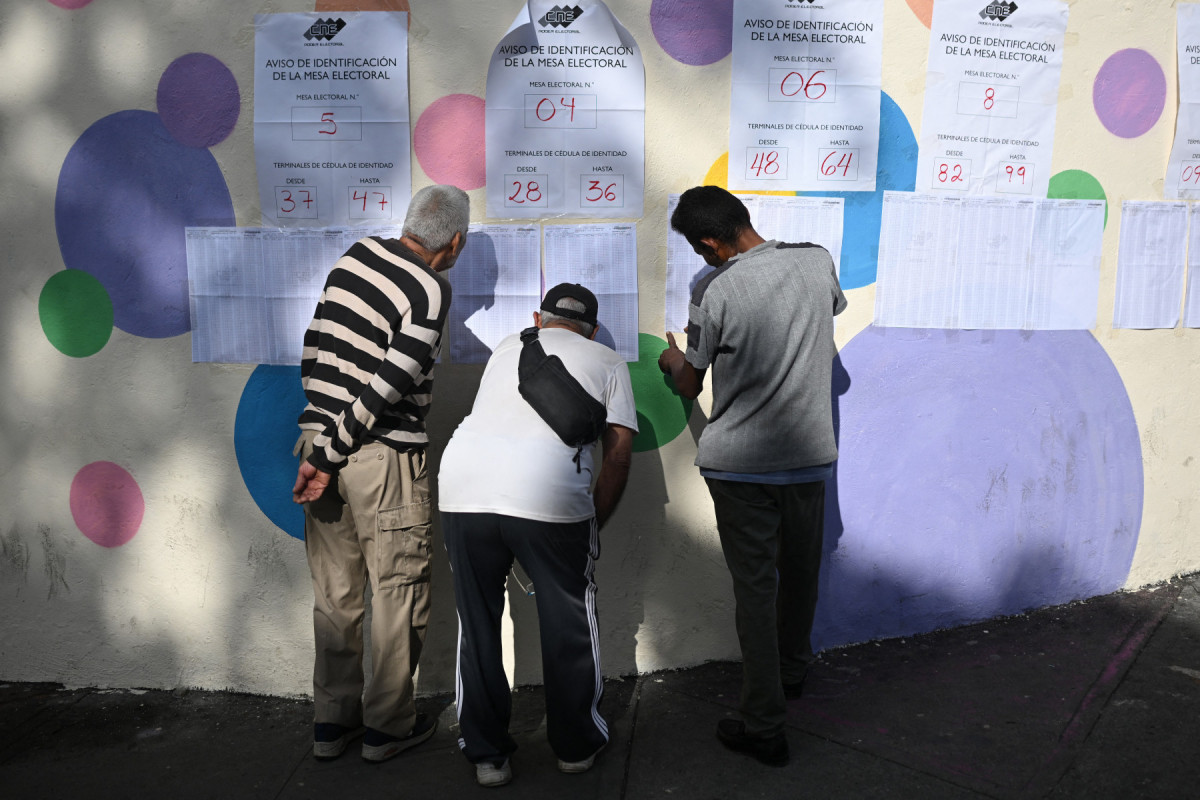 Pessoas verificam listas de votação do lado de fora de uma seção eleitoral durante as eleições regionais em Caracas