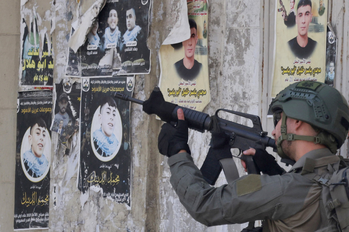 Um soldado do exército israelense aponta seu rifle durante um ataque no coração da cidade palestina de Nablus, na Cisjordânia ocupada, em 27 de maio de 2025. Em 27 de maio, as forças israelenses invadiram lojas de câmbio em várias cidades da Cisjordânia, incluindo Ramallah e Nablus, acusando sua empresa controladora de Um soldado do exército israelense aponta seu rifle durante um ataque no coração da cidade palestina de Nablus, na Cisjordânia ocupada, em 27 de maio de 2025. Em 27 de maio, as forças israelenses invadiram lojas de câmbio em várias cidades da Cisjordânia, incluindo Ramallah e Nablus, acusando sua empresa controladora de