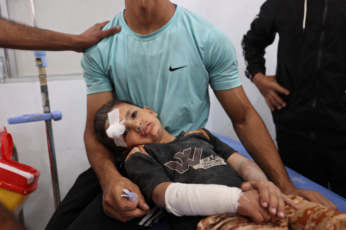 Conteúdo gráfico / Um homem conforta uma criança ferida após receber tratamento no Hospital Al-Awda, no campo de refugiados de Nuseirat, no centro da Faixa de Gaza, após um ataque aéreo israelense que atingiu uma escola no campo em 19 de maio de 2025. Equipes de resgate em Gaza disseram que ataques aéreos israelenses mataram pelo menos 22 pessoas em todo o território palestino em 19 de maio, enquanto os militares expandiam sua ofensiva. Em Nuseirat, três membros da mesma família foram mortos em um ataque aéreo à sua barraca. 