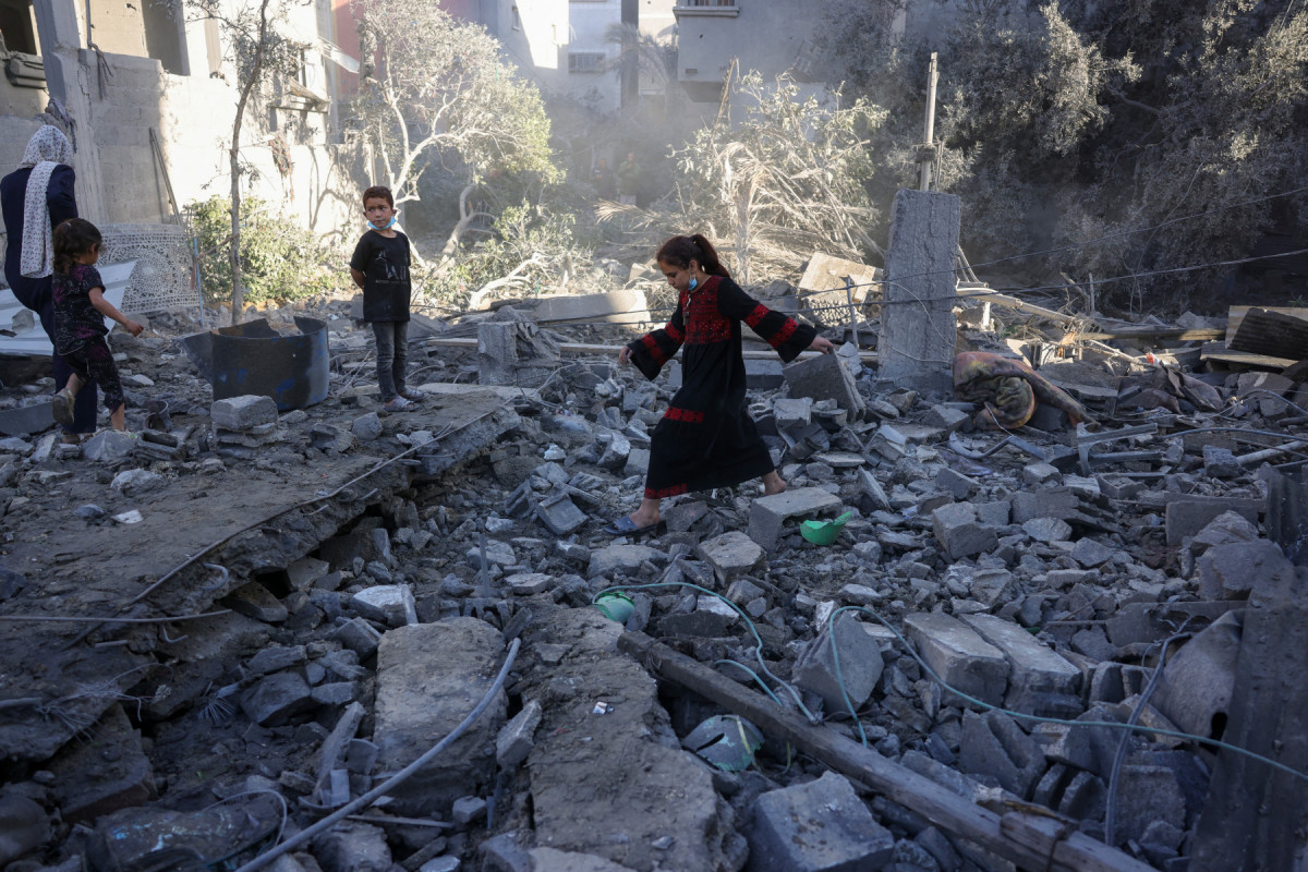 Menina caminha sobre os destroços enquanto palestinos verificam o local de um ataque israelense durante a noite, em Jabalia, no centro da Faixa de Gaza