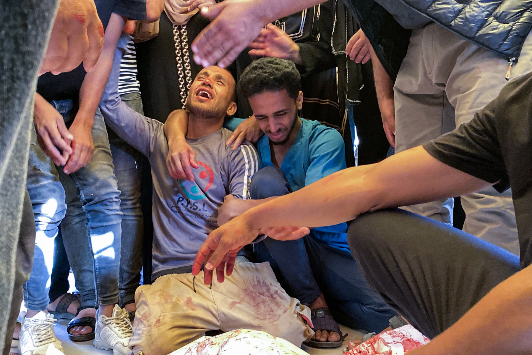 
Palestinos choram as mortes de parentes perto de um centro de distribuição de ajuda humanitária no sul de Gaza