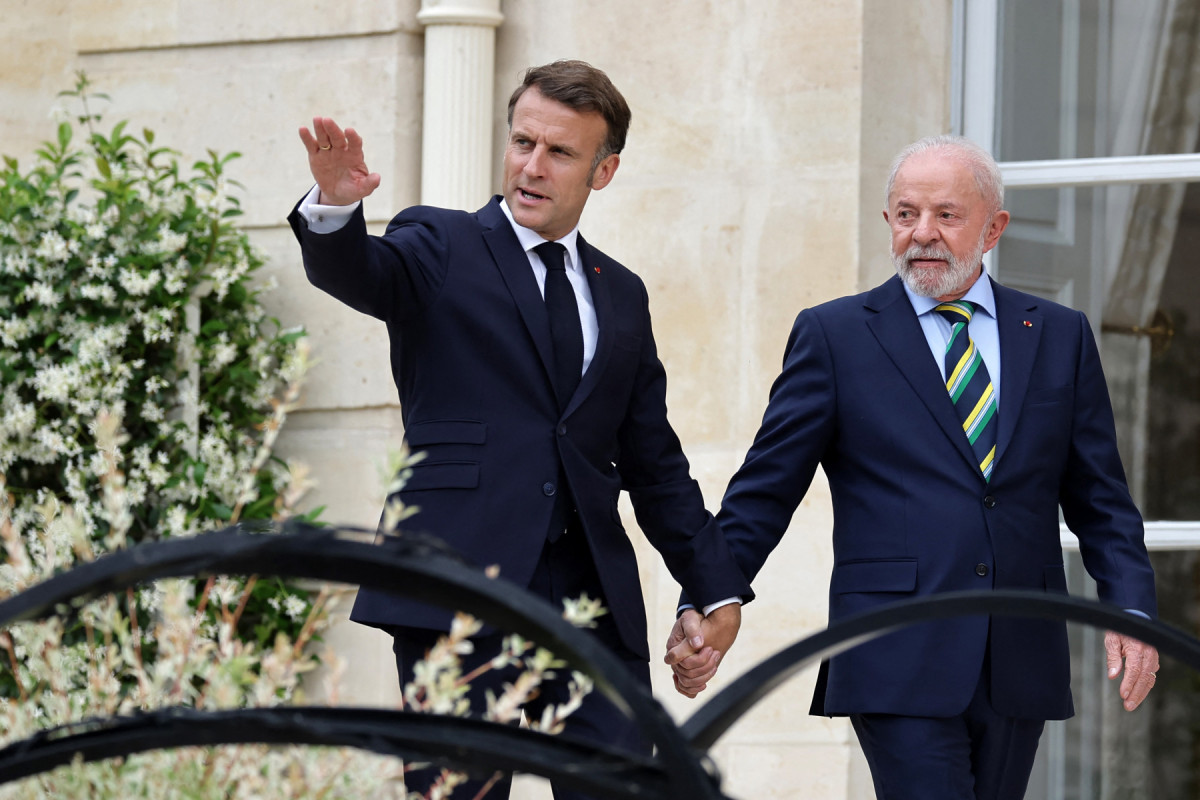 O presidente francês, Emmanuel Macron (E), e o presidente brasileiro, Luiz Inácio Lula da Silva, caminham após uma coletiva de imprensa conjunta após uma reunião no Palácio do Eliseu, em Paris,