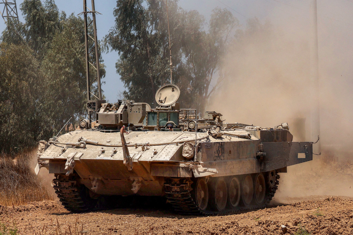 Um veículo blindado de transporte de pessoal israelense (APC) se move ao longo da cerca na fronteira sul de Israel com a Faixa de Gaza, em 5 de junho de 2025, em meio à guerra entre Israel e o Hamas. A agência de defesa civil de Gaza informou que ataques israelenses mataram pelo menos 10 pessoas no território palestino devastado em 5 de junho, enquanto os militares mantêm uma ofensiva intensificada. (Foto de Jack GUEZ / AFP)