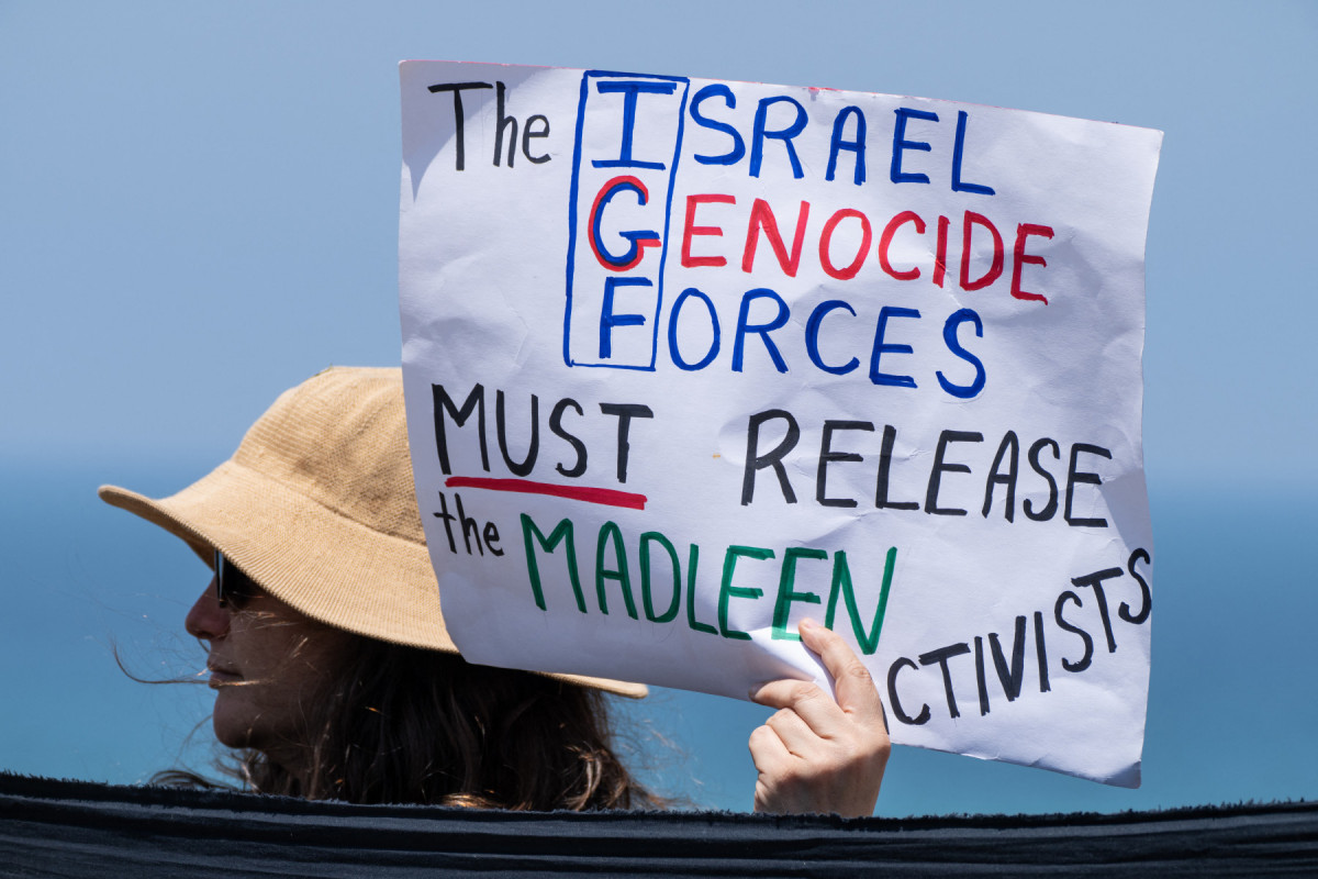 Um manifestante segura um cartaz durante uma reunião perto do porto israelense de Ashdod, em 9 de junho de 2025, após forças israelenses interceptarem um barco de ajuda humanitária com destino a Gaza. Forças israelenses interceptaram um barco de ajuda humanitária com destino a Gaza em 9 de junho, impedindo os ativistas a bordo — incluindo a ativista sueca Greta Thunberg — de chegarem ao território palestino bloqueado. (Foto de MAYA LEVIN / AFP)