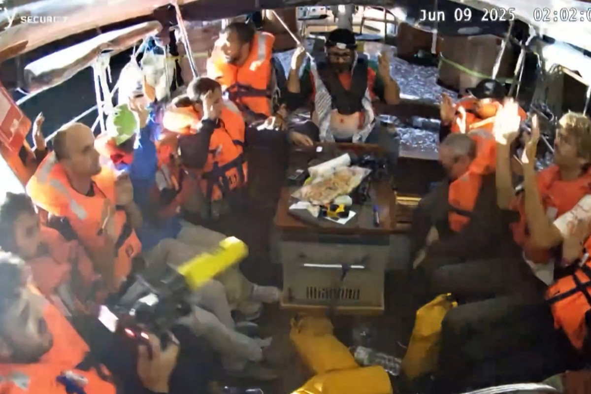 Uma imagem capturada de um vídeo divulgado pela Coalizão da Flotilha da Liberdade em 9 de junho de 2025 mostra ativistas a bordo do barco de ajuda humanitária Madleen, com as mãos no ar, com destino a Gaza, sendo interceptados pelas forças israelenses em águas internacionais antes de chegarem ao território palestino bloqueado. O barco foi redirecionado para a costa israelense, impedindo que os ativistas a bordo, incluindo a ativista sueca Greta Thunberg e a parlamentar europeia Rima Hassan, chegassem à Faixa de Gaza. (Foto da Coalizão da Flotilha da Liberdade / AFP) ( AFP) Uma imagem capturada de um vídeo divulgado pela Coalizão da Flotilha da Liberdade em 9 de junho de 2025 mostra ativistas a bordo do barco de ajuda humanitária Madleen, com as mãos no ar, com destino a Gaza, sendo interceptados pelas forças israelenses em águas internacionais antes de chegarem ao território palestino bloqueado. O barco foi redirecionado para a costa israelense, impedindo que os ativistas a bordo, incluindo a ativista sueca Greta Thunberg e a parlamentar europeia Rima Hassan, chegassem à Faixa de Gaza. (Foto da Coalizão da Flotilha da Liberdade / AFP)/ AFP