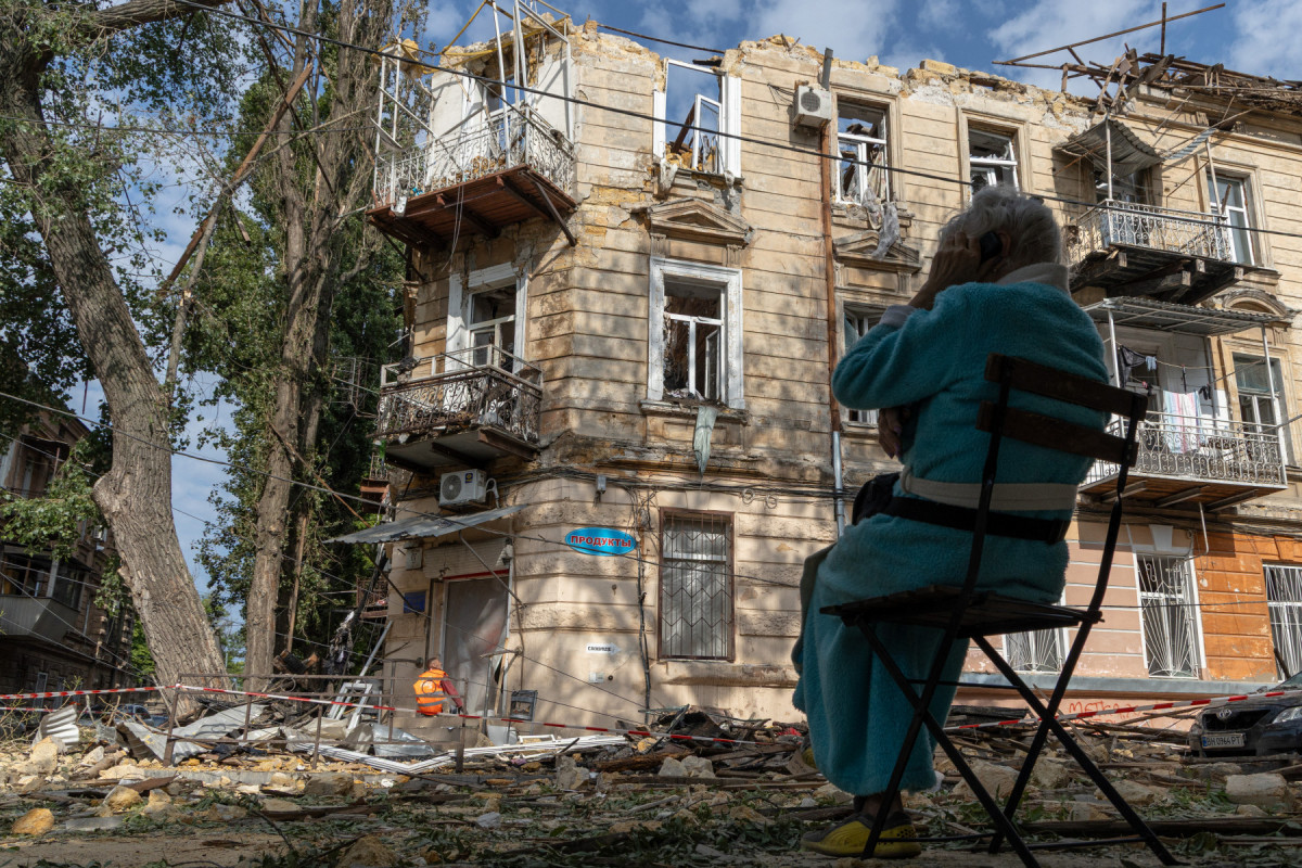 Uma mulher sentada ao lado de um prédio residencial danificado após um ataque de drones em Odessa, em 10 de junho de 2025, em meio à invasão russa na Ucrânia. A Rússia realizou ataques 