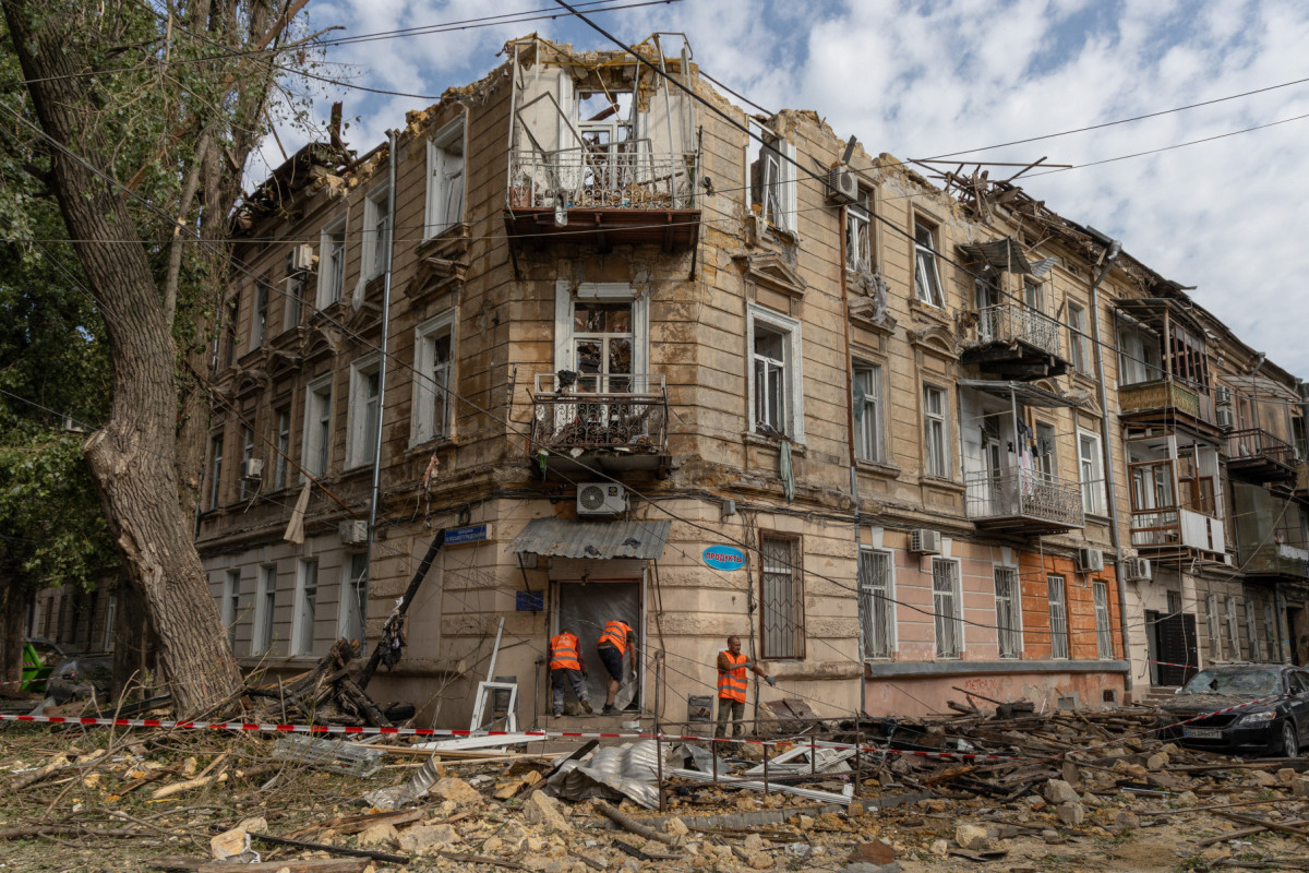 Trabalhadores comunitários limpam escombros ao lado de um prédio residencial danificado após um ataque de drones em Odessa, em 10 de junho de 2025, em meio à invasão russa na Ucrânia. A Rússia realizou ataques 