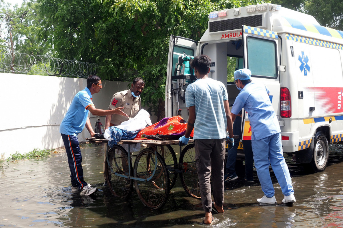 Policial e médicos transferem corpos de vítimas para uma ambulância 