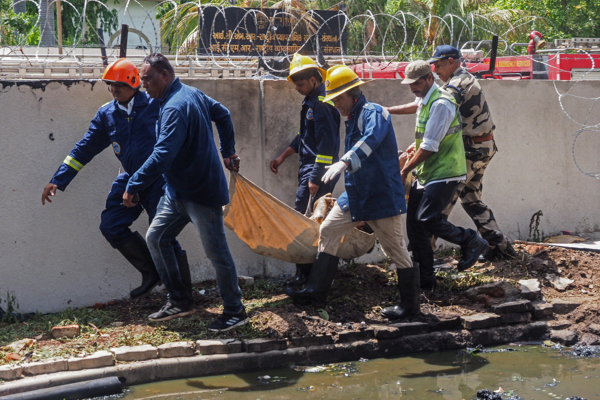 Bombeiros carregam o corpo de uma vítima após o voo 171 da Air India cair em uma área residencial perto do aeroporto de Ahmedabad, em 12 de junho de 2025. O avião de passageiros com destino a Londres caiu em 12 de junho na cidade de Ahmedabad, no oeste da Índia, com 242 pessoas a bordo, disseram autoridades da aviação, no que a companhia aérea chamou de Bombeiros carregam o corpo de uma vítima após o voo 171 da Air India cair em uma área residencial perto do aeroporto de Ahmedabad, em 12 de junho de 2025. O avião de passageiros com destino a Londres caiu em 12 de junho na cidade de Ahmedabad, no oeste da Índia, com 242 pessoas a bordo, disseram autoridades da aviação, no que a companhia aérea chamou de
