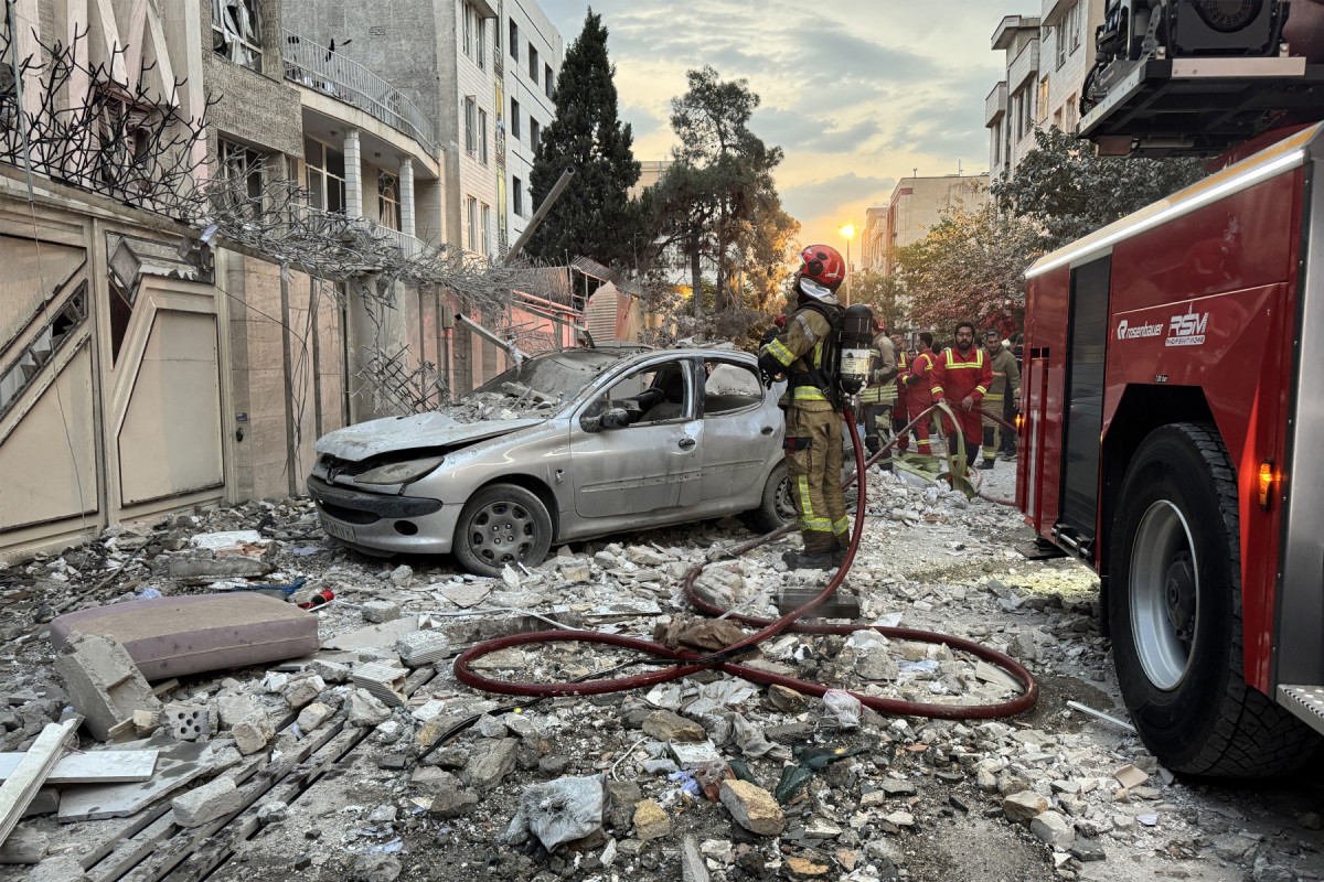
Equipes de emergência se reúnem em frente a um prédio atingido por um ataque israelense em Teerã em 13 de junho de 2025. Israel atingiu cerca de 100 alvos no Irã em 13 de junho, incluindo instalações nucleares e centros de comando militar, matando figuras importantes, como o chefe das Forças Armadas e importantes cientistas nucleares. (Foto de MEGHDAD MADADI / TASNIM NEWS / AFP)