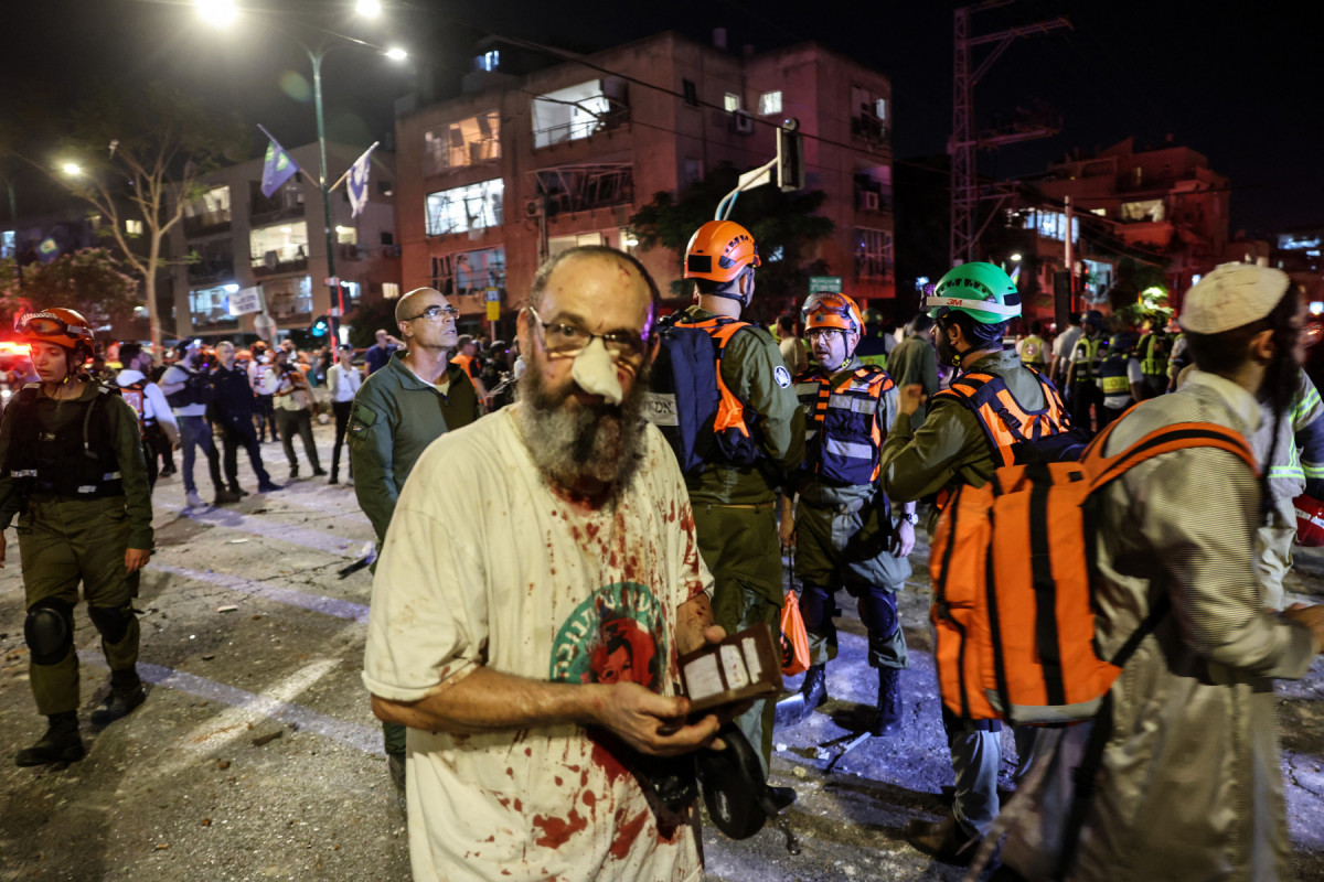 Um homem ferido está entre os socorristas em uma área atingida por um míssil disparado do Irã, em Ramat Gan, perto de Tel Aviv, nesta sexta-feira. ( AFP) Um homem ferido está entre os socorristas em uma área atingida por um míssil disparado do Irã, em Ramat Gan, perto de Tel Aviv, nesta sexta-feira. / AFP