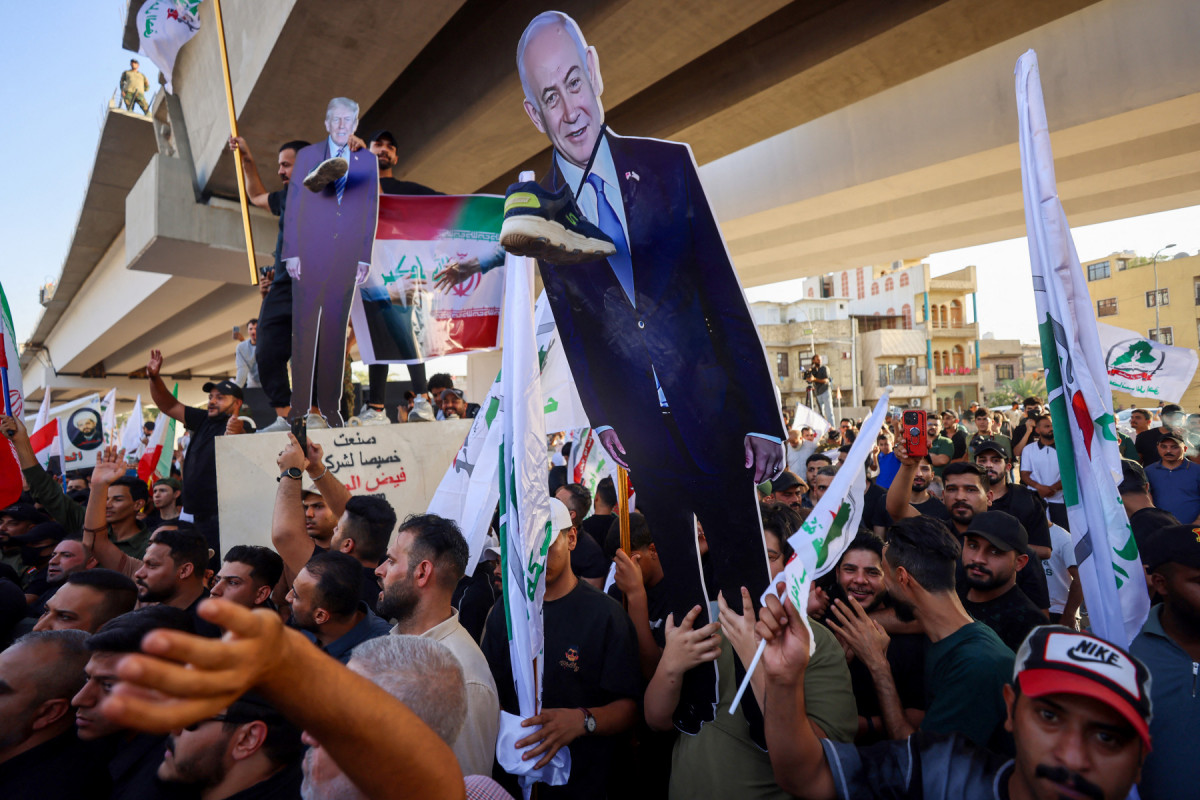 Apoiadores de grupos iraquianos pró-Irã seguram um recorte do presidente dos EUA, Donald Trump, e do primeiro-ministro israelense, Benjamin Netanyahu, durante um protesto em apoio ao Irã, em Bagdá, perto de uma ponte que leva à Zona Verde, o bairro ultrasseguro que abriga a embaixada dos EUA, em 16 de junho de 2025, em meio à escalada do conflito entre Israel e o Irã. (Foto de AHMAD AL-RUBAYE / AFP)