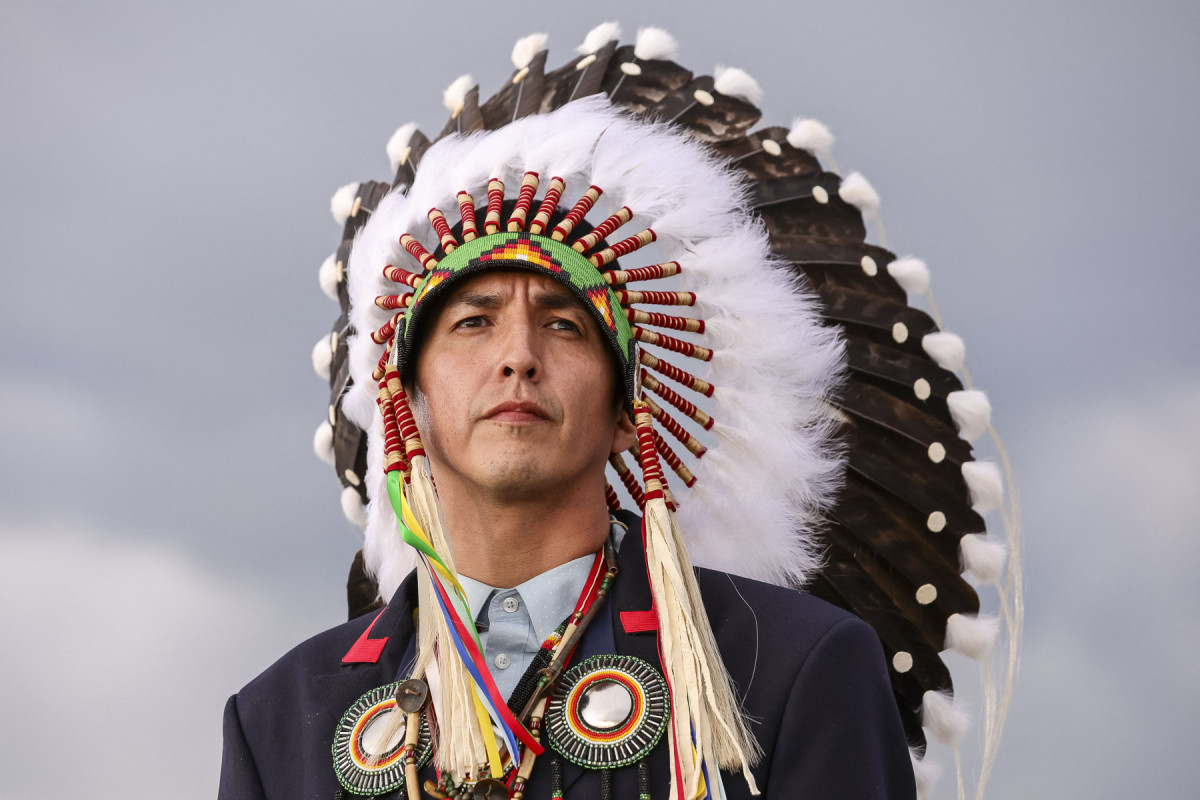 Steven Crowchild, da Primeira Nação Tsuut'ina, aguarda a chegada do presidente da França no Aeroporto Internacional de Calgary, antes do início da cúpula do G7