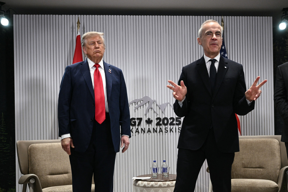 O presidente dos EUA, Donald Trump, observa enquanto o primeiro-ministro canadense, Mark Carney, diz à imprensa que eles não estão respondendo a perguntas, após a reunião individual e antes da reunião bilateral ampliada durante a Cúpula do G7