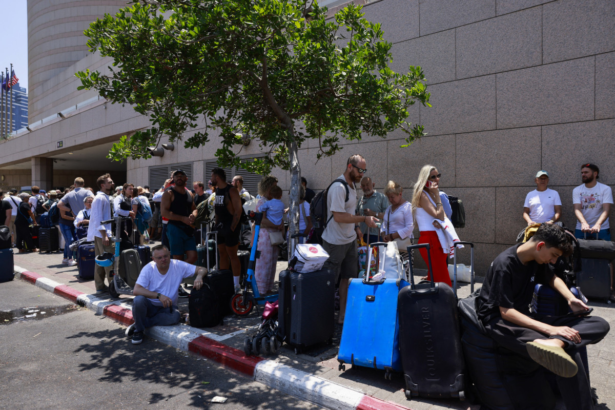 Pessoas chegam com suas bagagens antes da partida dos ônibus que transportarão portadores de passaportes estrangeiros, principalmente europeus e poloneses, para fora de Israel, em um ponto de encontro em Tel Aviv, em 17 de junho de 2025. A operação, coordenada pela embaixada polonesa, visa evacuar centenas de pessoas que embarcarão em ônibus com destino ao Sinai, no Egito, e de lá seguirão para Varsóvia, na Polônia. (Foto de Menahem KAHANA / AFP) ( AFP) Pessoas chegam com suas bagagens antes da partida dos ônibus que transportarão portadores de passaportes estrangeiros, principalmente europeus e poloneses, para fora de Israel, em um ponto de encontro em Tel Aviv, em 17 de junho de 2025. A operação, coordenada pela embaixada polonesa, visa evacuar centenas de pessoas que embarcarão em ônibus com destino ao Sinai, no Egito, e de lá seguirão para Varsóvia, na Polônia. (Foto de Menahem KAHANA / AFP)/ AFP