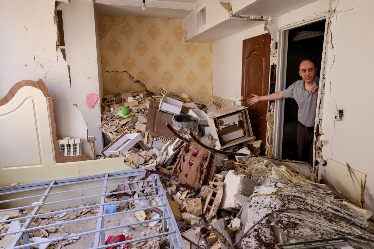 
Um morador gesticula enquanto mostra a destruição em seu prédio após ter sido atingido por um ataque israelense, em Teerã, em 25 de junho de 2025. Um frágil cessar-fogo na guerra Irã-Israel parecia se manter em 25 de junho, após 12 dias de ataques que levaram Israel e os Estados Unidos a bombardear as instalações nucleares da República Islâmica. (Foto de ATTA KENARE / AFP)
