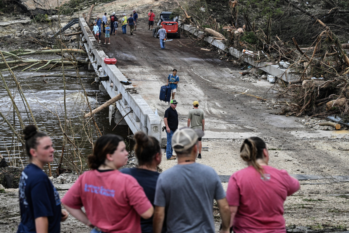  People look on as law enforcement and volunteers continue to search for missing people near Camp Mystic, the site of where at least 20 girls went missing after flash flooding in Hunt, Texas, on July 5, 2025. Rescuers were on Saturday searching for more than 20 girls missing from a riverside summer camp in the US state of Texas, after torrential rains caused devastating flooding that killed at least 27 people -- with more rain on the way. 
