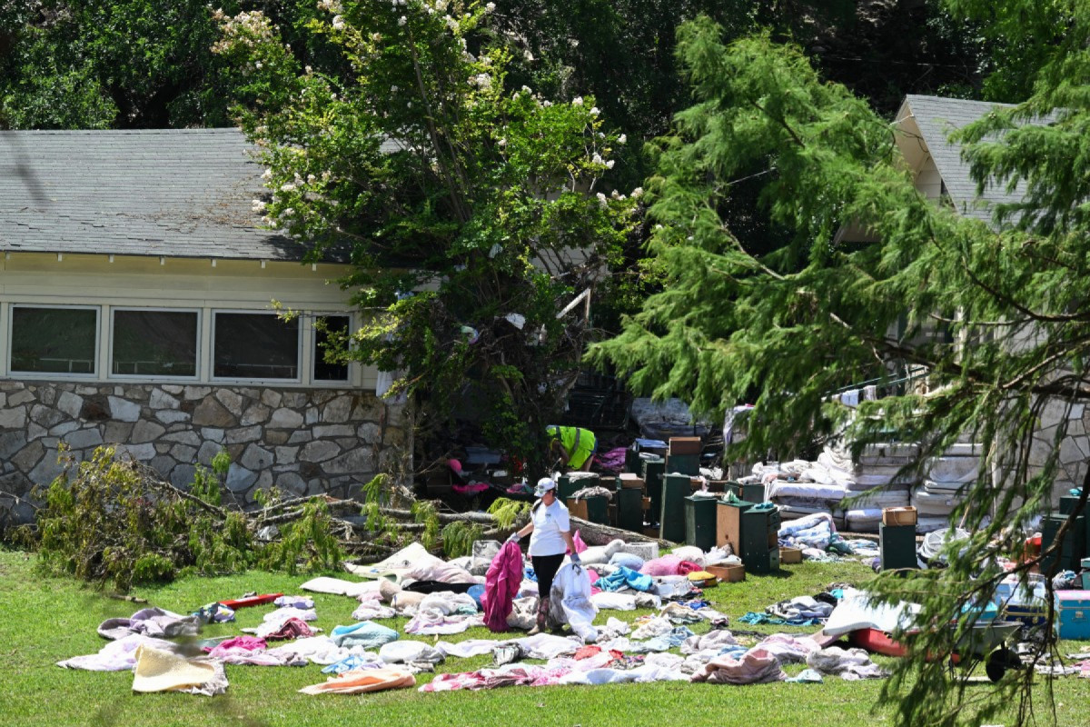 Uma mulher separa roupas e pertences dos campistas do lado de fora dos chalés do Acampamento Mystic, às margens do Rio Guadalupe, em Hunt, Texas, em 8 de julho de 2025, após graves inundações repentinas no feriado de 4 de julho.
As inundações catastróficas do fim de semana de 4 de julho deixaram mais de 100 mortos, incluindo mais de duas dúzias de meninas e monitores em um acampamento de verão à beira do rio, com equipes de resgate correndo em 8 de julho para procurar dezenas de pessoas ainda desaparecidas. (Foto de RONALDO SCHEMIDT / AFP)