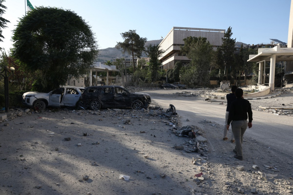  Men walk in front of the heavily damaged Syrian army and defence ministry headquarters in Damascus, following Israeli strikes on July 16, 2025. 