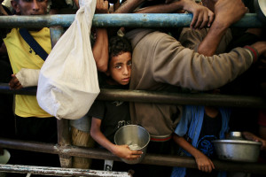 Um menino palestino aguarda uma refeição em uma cozinha beneficente na área de Mawasi, em Khan Yunis, no sul da Faixa de Gaza, em 22 de julho de 2025. O chefe do maior hospital de Gaza disse que 21 crianças morreram de desnutrição e fome no território palestino nos últimos três dias, em meio a um ataque devastador das forças israelenses. (Foto: AFP)