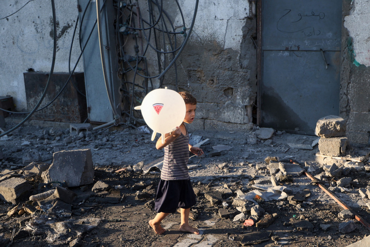Um menino palestino caminha entre os destroços após um ataque israelense ao campo de refugiados de Bureij, no centro da Faixa de Gaza, em 23 de julho de 2025. Mais de 100 organizações humanitárias alertaram, em 23 de julho, que a 