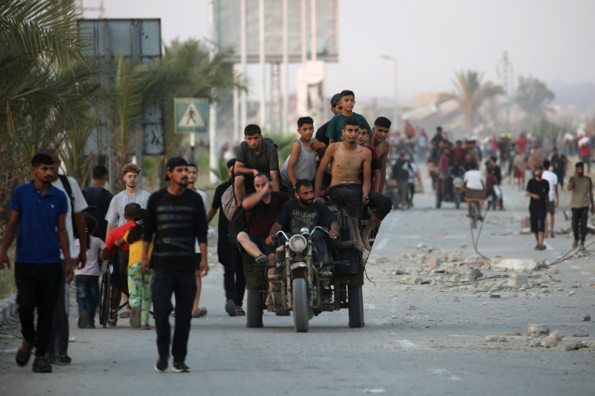 Palestinos caminham pela rua Al-Rashid, no oeste de Jabalia, em 23 de julho de 2025, após receberem ajuda humanitária de um ponto de distribuição no norte da Faixa de Gaza. Mais de 100 organizações humanitárias alertaram, em 23 de julho, que a 