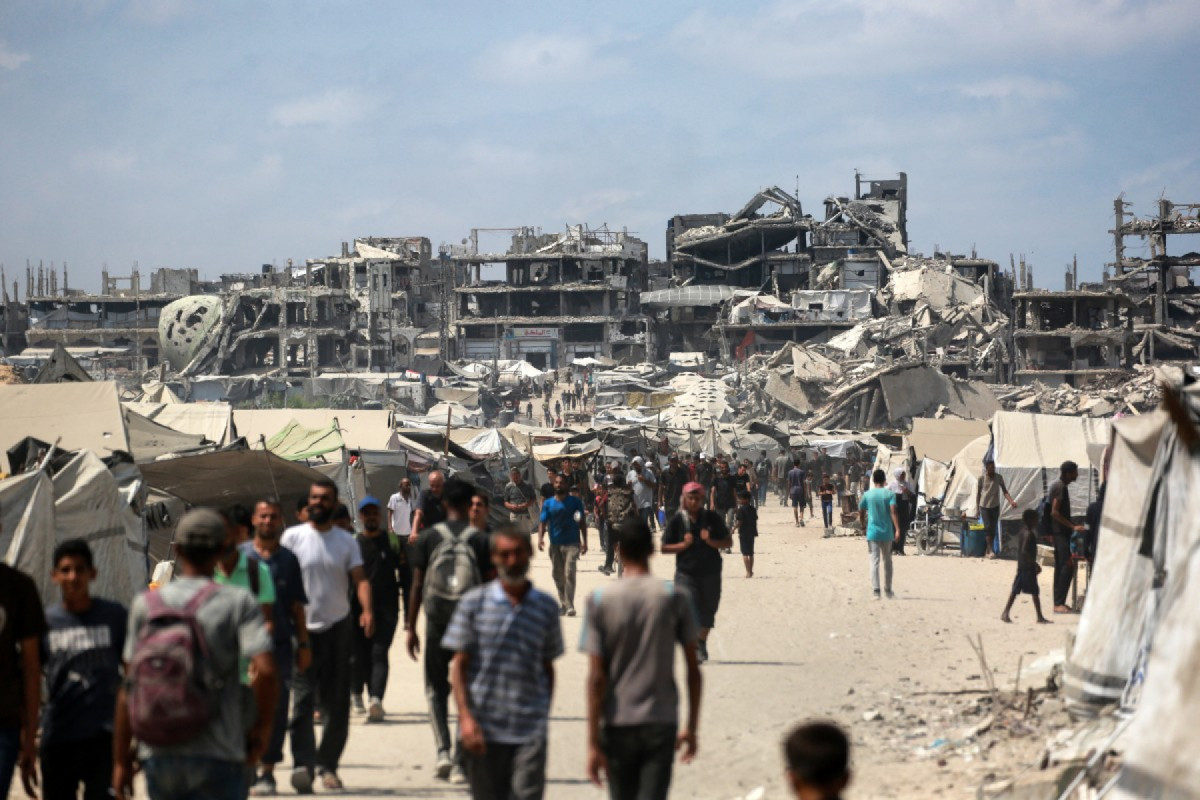 Palestinos caminham por uma rua perto de prédios danificados pela guerra na Cidade de Gaza, em 8 de agosto de 2025. O exército israelense 