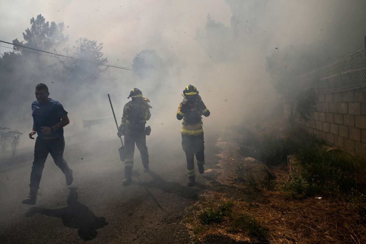 Pessoas combatem um incêndio florestal na vila de Vilarino, no município de Carballeda de Avia, noroeste da Espanha, em 17 de agosto de 2025. A Espanha está entrando em sua terceira semana de alertas de onda de calor e os bombeiros continuam combatendo as chamas no noroeste e oeste do país, com unidades do exército mobilizadas para ajudar a conter as chamas. França e Itália já haviam enviado bombardeiros de água para uma base aérea perto de Salamanca para ajudar nos esforços de combate ao fogo. (Foto de MIGUEL RIOPA / AFP)
( AFP) Pessoas combatem um incêndio florestal na vila de Vilarino, no município de Carballeda de Avia, noroeste da Espanha, em 17 de agosto de 2025. A Espanha está entrando em sua terceira semana de alertas de onda de calor e os bombeiros continuam combatendo as chamas no noroeste e oeste do país, com unidades do exército mobilizadas para ajudar a conter as chamas. França e Itália já haviam enviado bombardeiros de água para uma base aérea perto de Salamanca para ajudar nos esforços de combate ao fogo. (Foto de MIGUEL RIOPA / AFP)
/ AFP