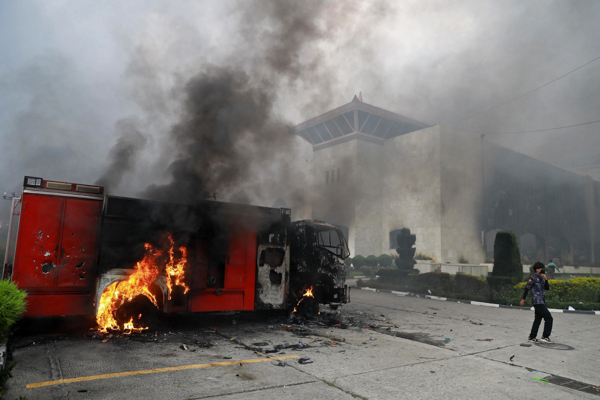 A woman walks past a burning vehicle, set ablaze by protesters inside the premises of the Parliament House in Kathmandu on September 9, 2025, a day after a police crackdown on demonstrations over social media prohibitions and corruption by the government. Nepal's president called for national unity on September 9, after two days of violent protests, including rallies against a government ban on social media that forced the prime minister to resign and left at least 19 people dead. ( Prabin RANABHAT / AFP) A woman walks past a burning vehicle, set ablaze by protesters inside the premises of the Parliament House in Kathmandu on September 9, 2025, a day after a police crackdown on demonstrations over social media prohibitions and corruption by the government. Nepal's president called for national unity on September 9, after two days of violent protests, including rallies against a government ban on social media that forced the prime minister to resign and left at least 19 people dead. / Prabin RANABHAT / AFP