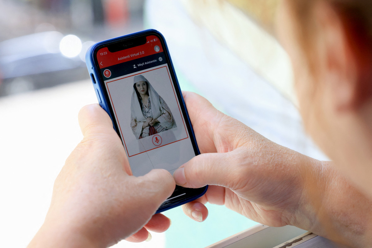 Uma mulher olha para um celular enquanto usa o portal do governo albanês Uma mulher olha para um celular enquanto usa o portal do governo albanês