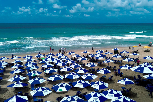  Itens que foram entregues aos barraqueiros na Praia de Boa Viagem sendo utilizados, como guarda-sol e cooler. 