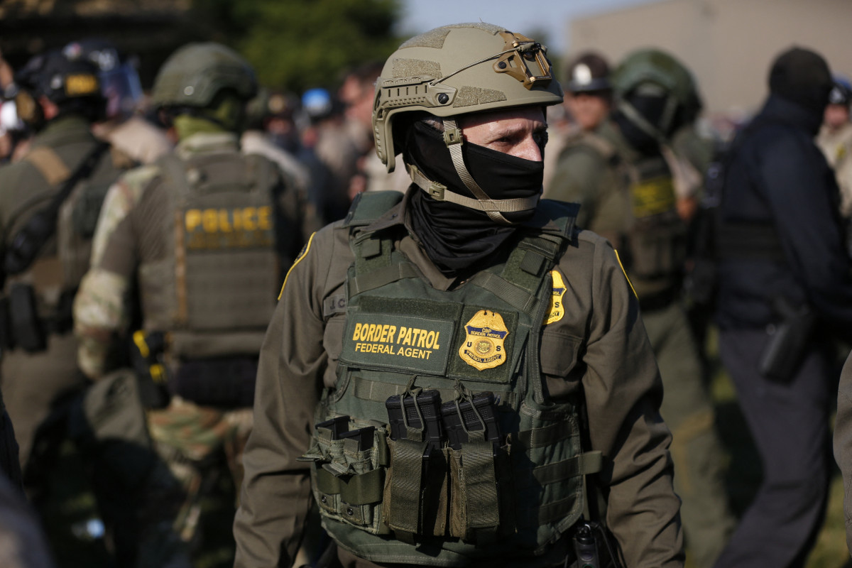 Agente da Alfândega e Proteção de Fronteiras dos EUA (CBP) monta guarda enquanto centenas de manifestantes se reúnem perto de uma instalação do Serviço de Imigração e Alfândega (ICE) se opõem à detenção de imigrantes indocumentados após a ordem do presidente Donald Trump de aumentar a presença federal e intensificar a fiscalização da imigração por meio do Departamento de Segurança Interna em Broadview, Illinois, em 3 de outubro de 2025. O presidente dos EUA, Donald Trump, que fez campanha prometendo deportar um grande número de migrantes, encorajou as autoridades a serem mais agressivas enquanto busca atingir sua meta amplamente divulgada de um milhão de deportações anualmente. (Foto de OCTAVIO JONES / AFP)/ AFP
