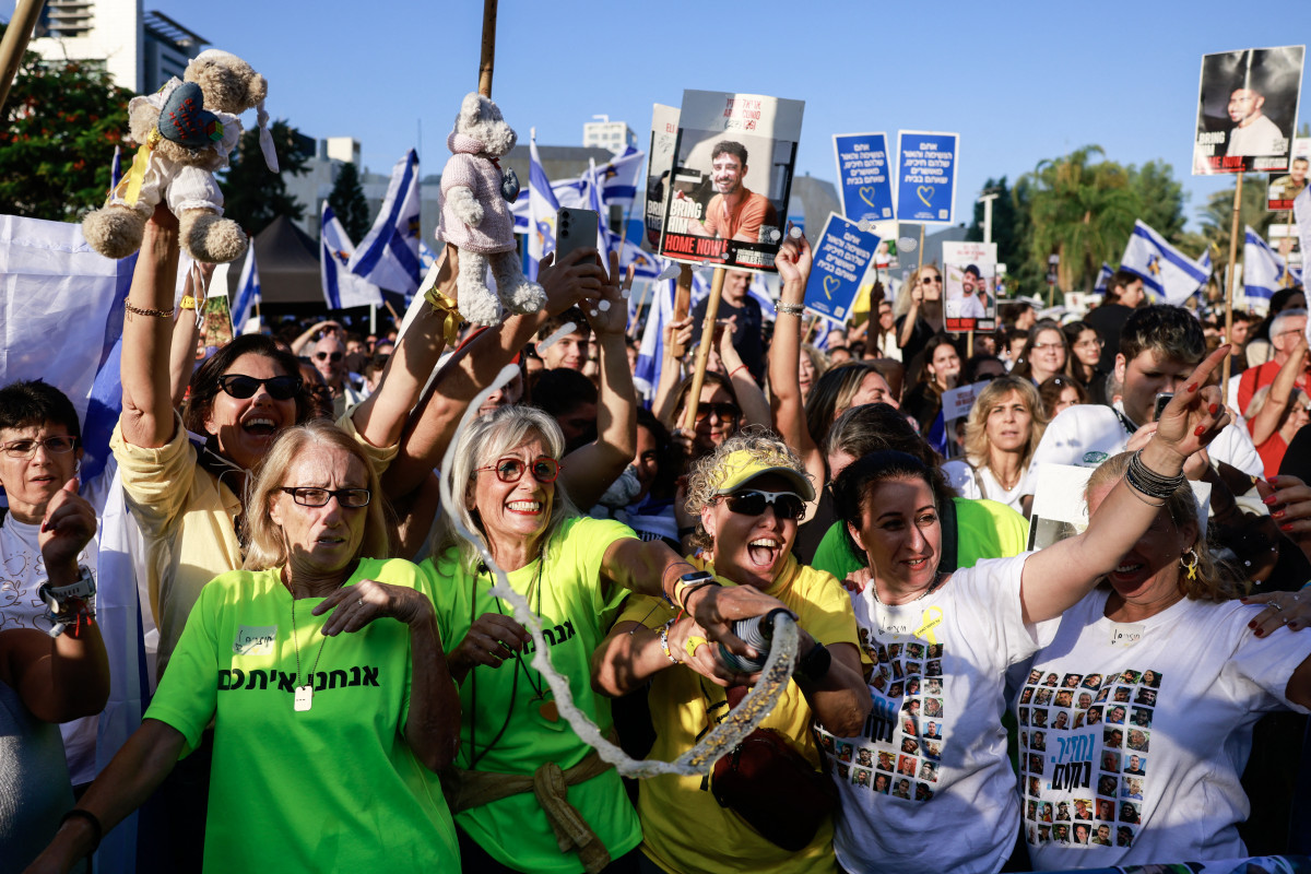 Pessoas comemoram na Praça dos Reféns, em Tel Aviv, após a notícia de que o Hamas já entregou sete reféns sobreviventes à Cruz Vermelha em 13 de outubro de 2025. O exército israelense recebeu, no mesmo dia, sete reféns libertados que haviam sido entregues anteriormente à Cruz Vermelha na Faixa de Gaza, segundo informaram as forças armadas e o serviço de segurança. De acordo com um acordo de cessar-fogo mediado pelo presidente dos Estados Unidos após dois anos de guerra, o Hamas deve libertar todos os reféns sobreviventes na segunda-feira, em troca de prisioneiros palestinos detidos por Israel. (Foto: Menahem Kahana / AFP) Pessoas comemoram na Praça dos Reféns, em Tel Aviv, após a notícia de que o Hamas já entregou sete reféns sobreviventes à Cruz Vermelha em 13 de outubro de 2025. O exército israelense recebeu, no mesmo dia, sete reféns libertados que haviam sido entregues anteriormente à Cruz Vermelha na Faixa de Gaza, segundo informaram as forças armadas e o serviço de segurança. De acordo com um acordo de cessar-fogo mediado pelo presidente dos Estados Unidos após dois anos de guerra, o Hamas deve libertar todos os reféns sobreviventes na segunda-feira, em troca de prisioneiros palestinos detidos por Israel./Foto: Menahem Kahana / AFP