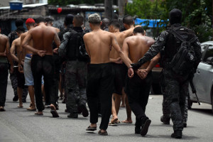 Policiais escoltam suspeitos presos durante a Operação Contenção para fora da favela da Vila Cruzeiro, no complexo da Penha, no Rio de Janeiro