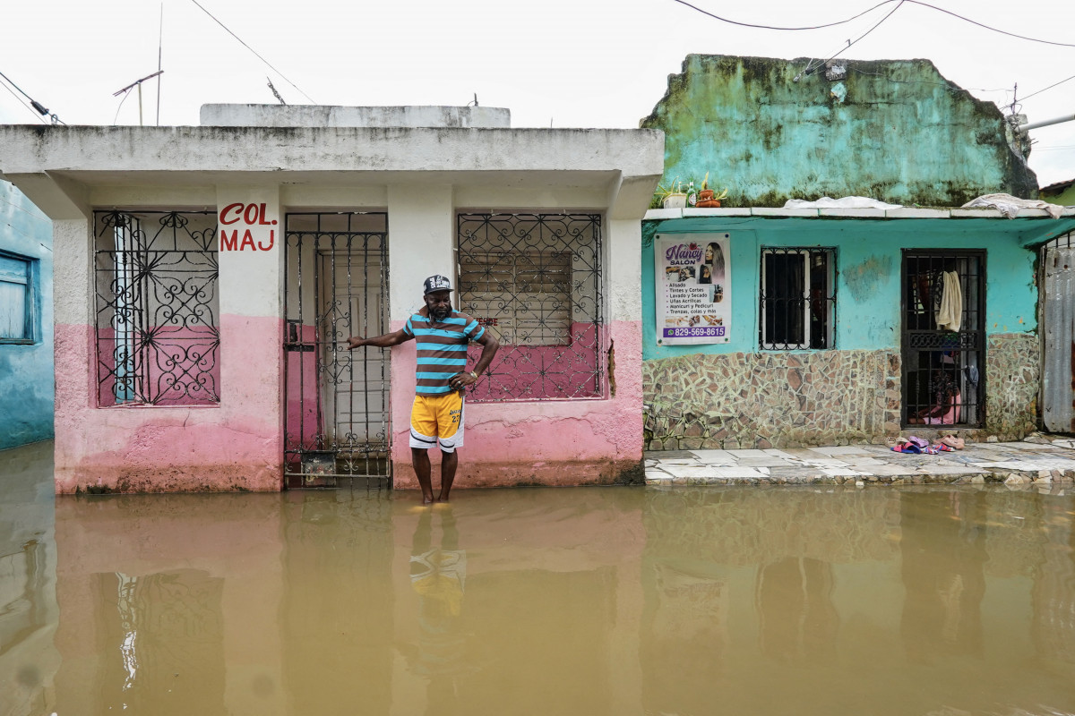 Um homem está ao lado de uma casa em uma rua alagada antes da chegada do furacão Melissa no bairro de Las Cucarachas em Santo Domingo, República Dominicana, em 28 de outubro de 2025. (Foto de Danny Polanco / AFP) ( AFP)