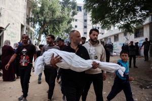 Conteúdo gráfico / Um homem carrega o corpo de uma criança morta em um ataque aéreo israelense durante a noite na Cidade de Gaza, em 29 de outubro de 2025. (Foto de Omar AL-QATTAA / AFP)