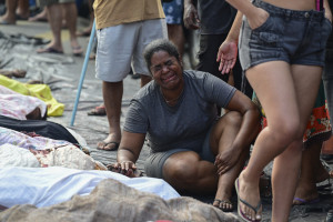 Conteúdo gráfico / Uma mulher chora ao lado de um homem morto, em meio a uma fileira de corpos, na Praça São Lucas, na favela Vila Cruzeiro, no Complexo da Penha, Rio de Janeiro, Brasil, em 29 de outubro de 2025, após a Operação Contenção. (Foto de Pablo Porciúncula / AFP)