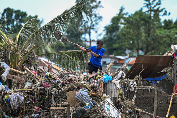 Moradores limpam suas casas danificadas após a passagem do tufão Kalmaegi em Talisay, na província de Cebu, em 5 de novembro de 2025. (Foto de Jam STA ROSA / AFP)