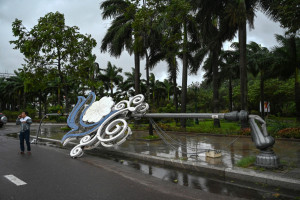 Um homem fala ao telefone ao lado de um poste de luz que desabou devido aos fortes ventos antes da chegada do tufão Kalmaegi, perto da praia de Quy Nhon, na província de Gia Lai, no centro do Vietnã, em 6 de novembro de 2025. A velocidade dos ventos do tufão Kalmaegi aumentava em 6 de novembro, enquanto ele se dirigia para o Vietnã, onde crescia o temor de que o tufão pudesse agravar os danos causados ??pelas inundações que já haviam deixado 47 mortos há uma semana. (Foto de NHAC NGUYEN / AFP)