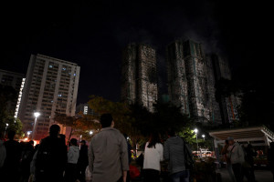 Testemunhas observam após um grande incêndio ter devastado vários blocos de apartamentos no conjunto residencial Wang Fuk Court, no distrito de Tai Po, em Hong Kong, em 27 de novembro de 2025. (Foto de Philip FONG / AFP)