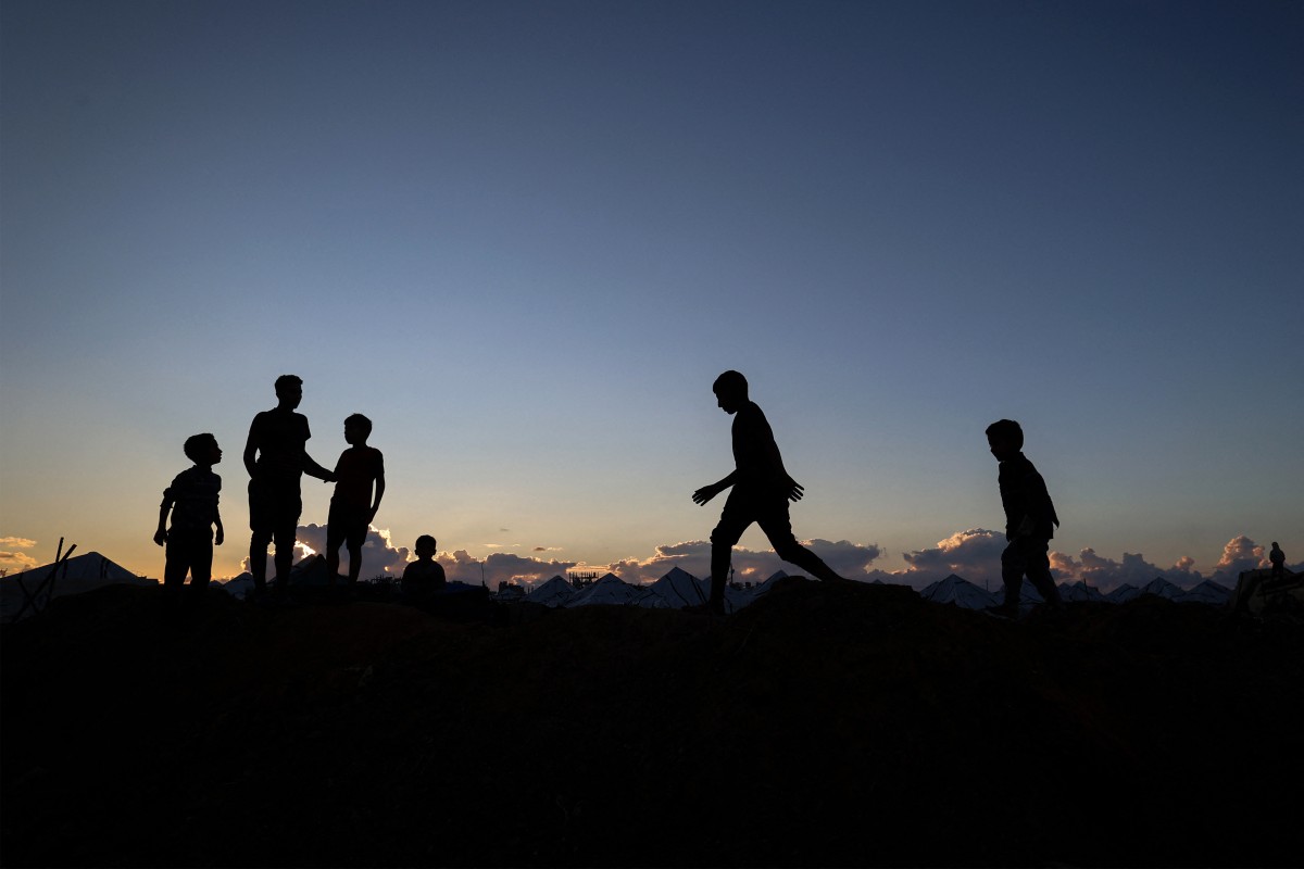 Crianças brincando são silhuetadas contra o céu no campo de Nuseirat para palestinos deslocados, na região central da Faixa de Gaza, em 2 de dezembro de 2025. O cessar-fogo, que entrou em vigor em 10 de outubro, permanece frágil, com Israel e o Hamas acusando-se mutuamente de violar os termos, enquanto a Faixa de Gaza continua em profunda crise humanitária. (Foto de Eyad Baba / AFP)/ AFP