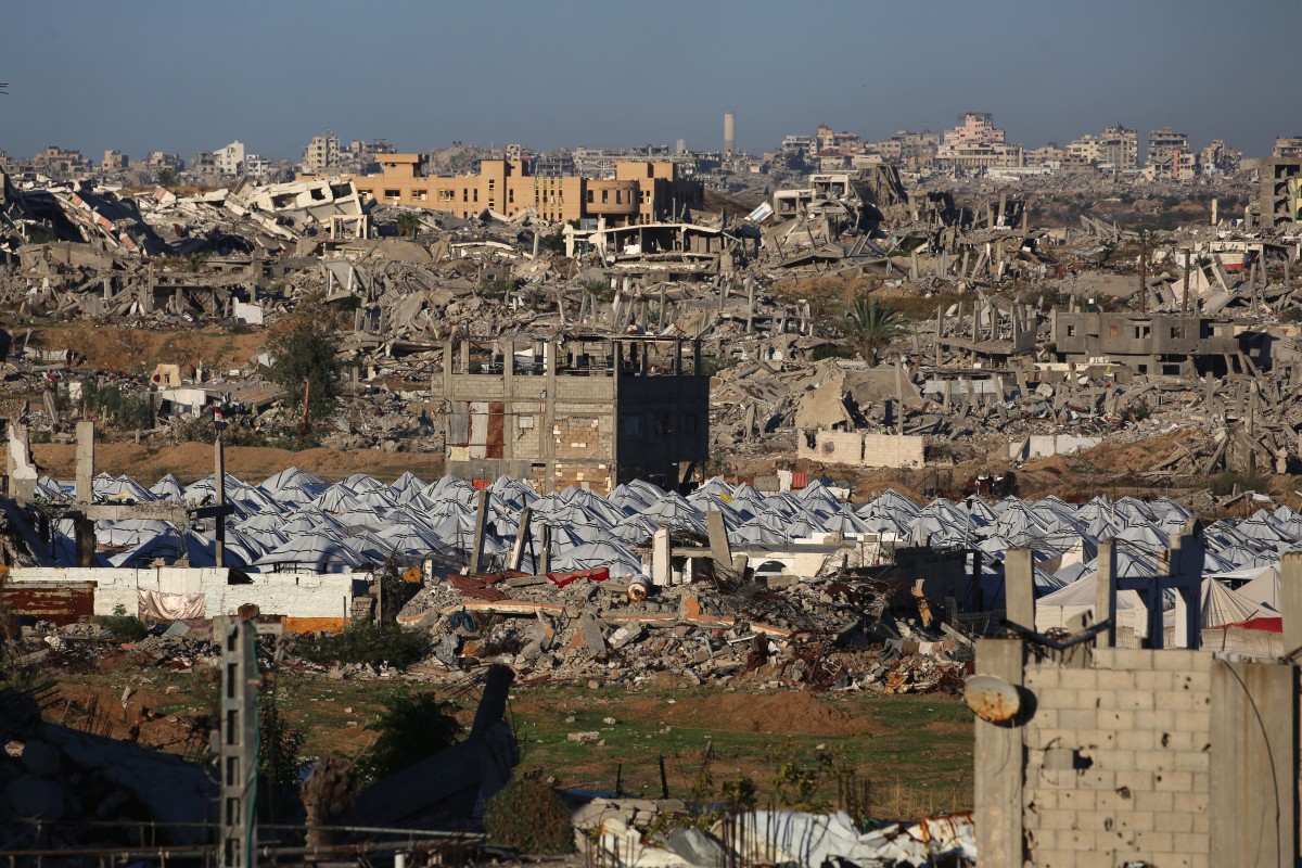 Esta imagem mostra um acampamento em meio aos escombros de edifícios destruídos no campo de Nuseirat, para palestinos deslocados, na região central da Faixa de Gaza, em 2 de dezembro de 2025. O cessar-fogo, que entrou em vigor em 10 de outubro, permanece frágil, com Israel e o Hamas acusando-se mutuamente de violar os termos, enquanto a Faixa de Gaza continua em profunda crise humanitária. (Foto de Eyad Baba / AFP)/ AFP