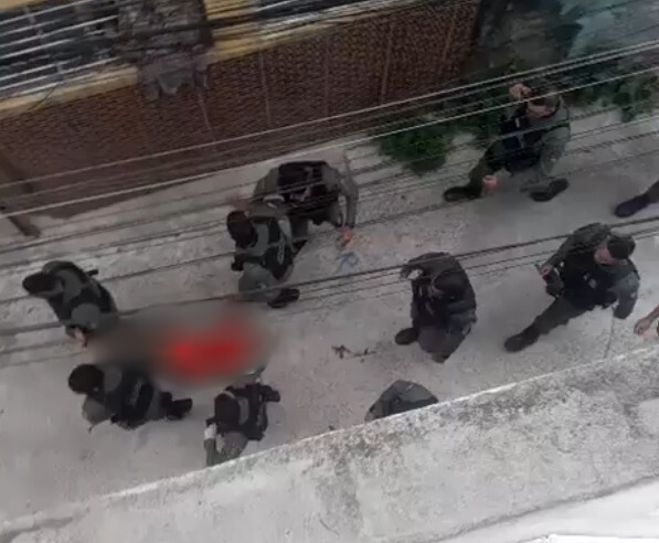 Policiais carregam o corpo de homem baleado./Foto: Reprodução