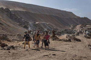 Grupo de homens e mulheres atravessa uma &aacute;rea de minera&ccedil;&atilde;o em 26 de maio de 2025 em Kolwezi, Rep&uacute;blica Democr&aacute;tica do Congo