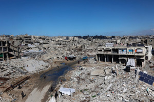 Palestinos caminham em meio aos escombros de pr&eacute;dios destru&iacute;dos no bairro de Sheikh Radwan, na Cidade de Gaza, em 4 de fevereiro de 2026. Apesar de uma tr&eacute;gua mediada pelos EUA ter entrado em sua segunda fase no in&iacute;cio de janeiro, a viol&ecirc;ncia no territ&oacute;rio palestino continuou, com Israel e o Hamas acusando-se mutuamente de violar o acordo. (Foto de Omar AL-QATTAA / AFP)