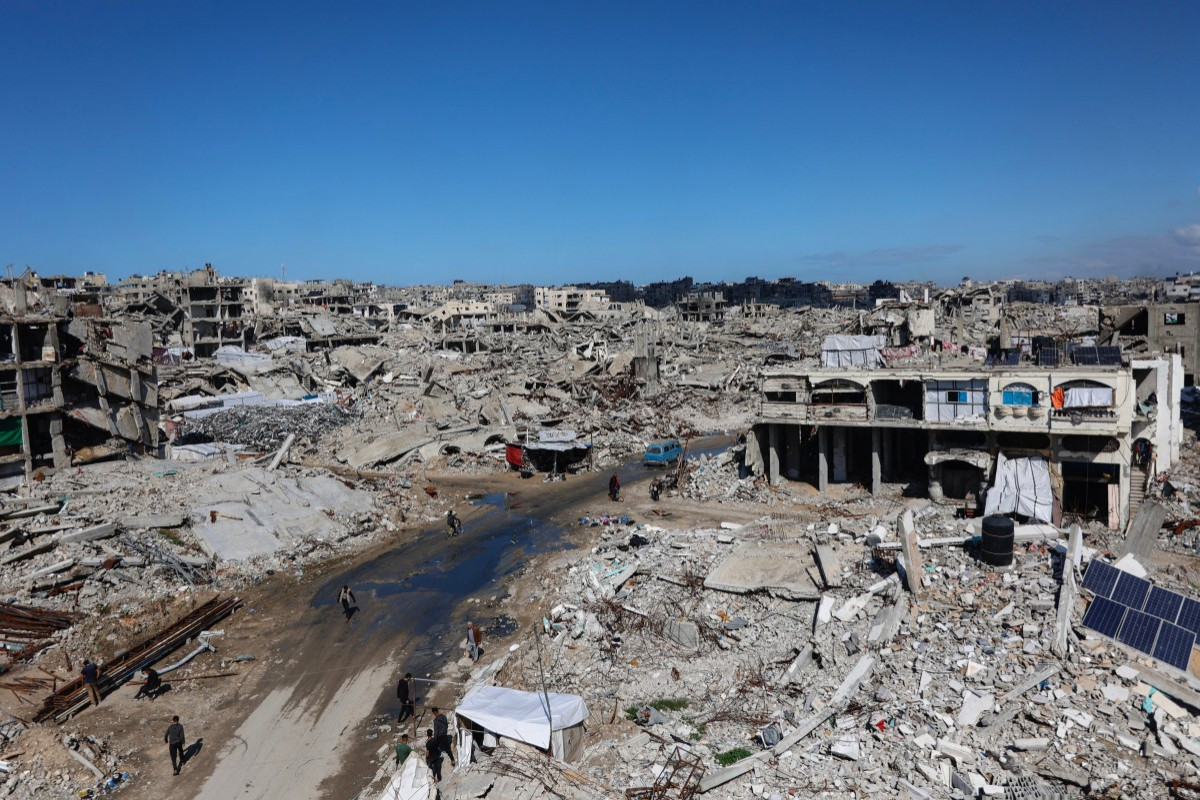 Palestinos caminham em meio aos escombros de prédios destruídos no bairro de Sheikh Radwan, na Cidade de Gaza, em 4 de fevereiro de 2026. Apesar de uma trégua mediada pelos EUA ter entrado em sua segunda fase no início de janeiro, a violência no território palestino continuou, com Israel e o Hamas acusando-se mutuamente de violar o acordo. (Foto de Omar AL-QATTAA / AFP)/ AFP